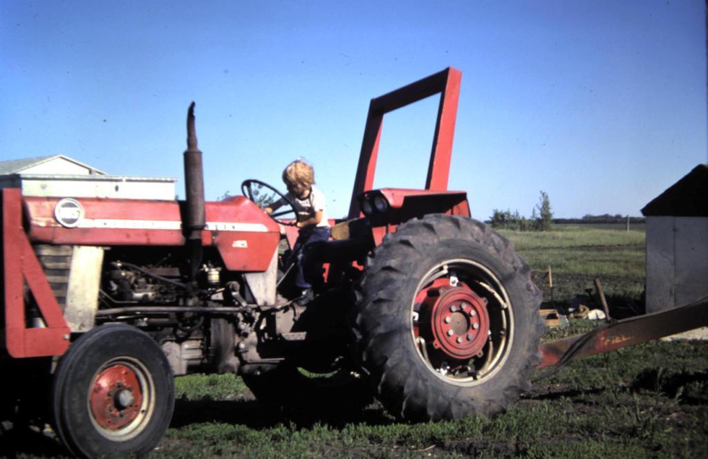 Young boy sitting on a farm tractor in 1979.